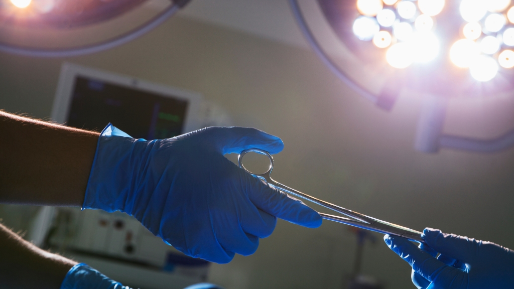 Close-up of surgeon’s hands passing medical scissors.