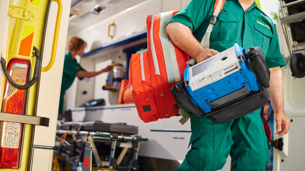 A paramedic in uniform holds a medical bag, prepared to provide medical assistance.