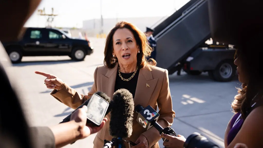 Kamala Harris speaks to reporters who are holding multiple microphones.