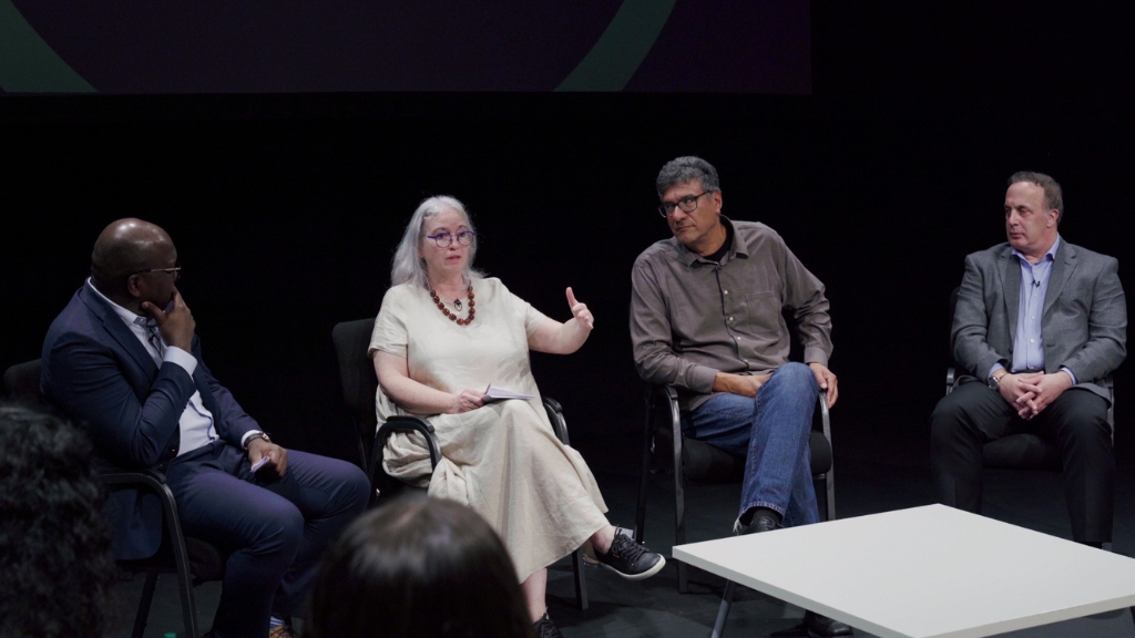 A gathering of diverse individuals seated on chairs in a room, engaged in thoughtful conversation.